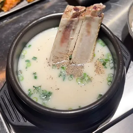 白濁したスープに青ねぎが浮かび、大きな牛骨が添えられた温かい料理です。