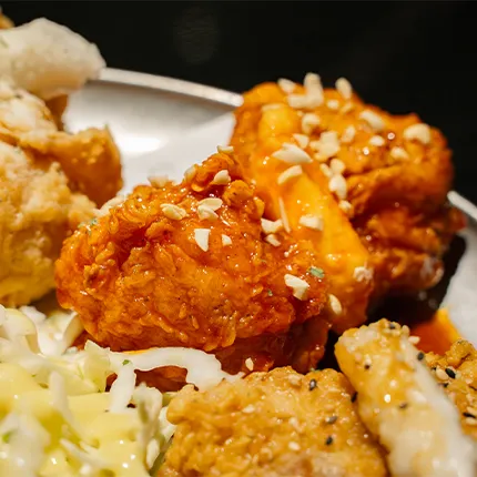 甘辛いソースをまとった韓国チキンが香ばしく揚がり、ナッツが散らされています。