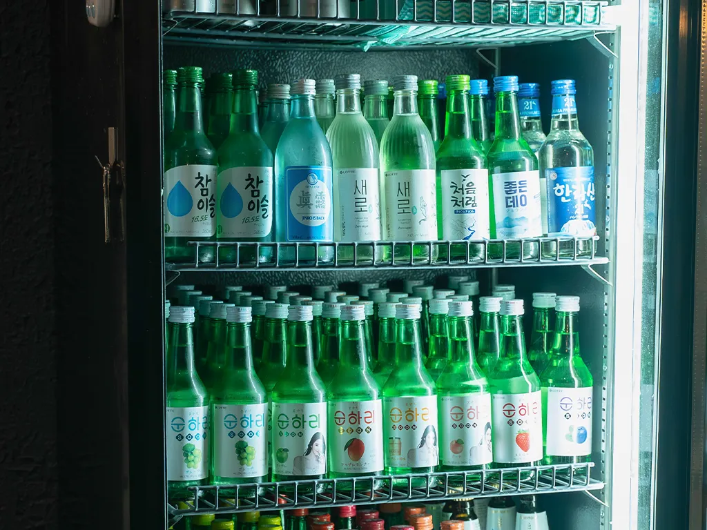 冷蔵庫の中に並べられたさまざまな種類の韓国焼酎のボトルが見える